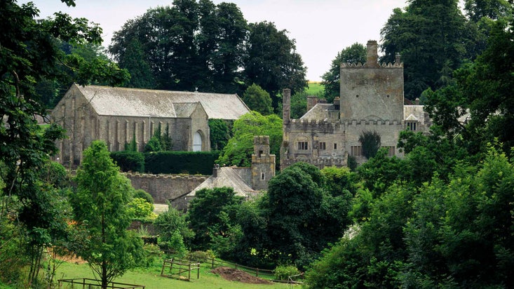 A panoramic view of Buckland Abbey seen from the north. The Great Barn stands out prominently to the left.